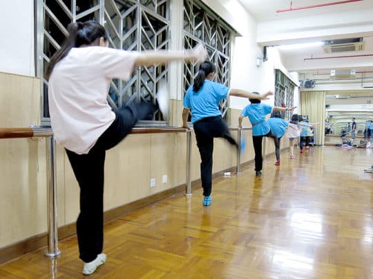 女學員們靠在扶手上練習踢腿。