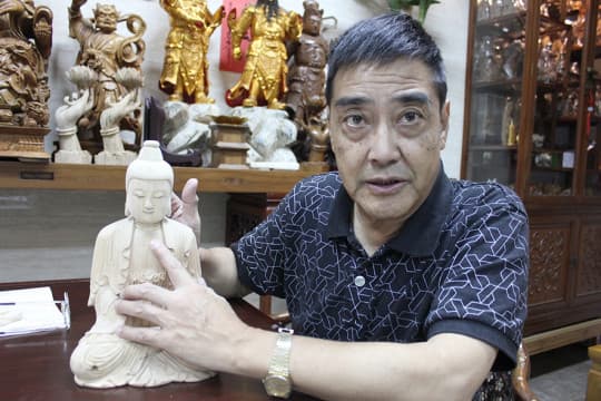 百年老店「大昌佛像雕刻木器」負責人 曾德衡展示大昌木雕佛像模型。
