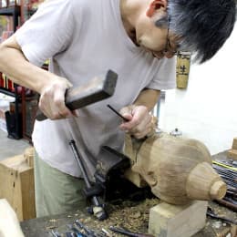 「大昌佛像雕刻木器」負責人 曾德衡展示木雕佛像模型的頭部。