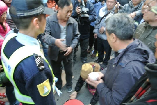 與警方多次周旋，女戶主突跪在地上阻止警員前行。