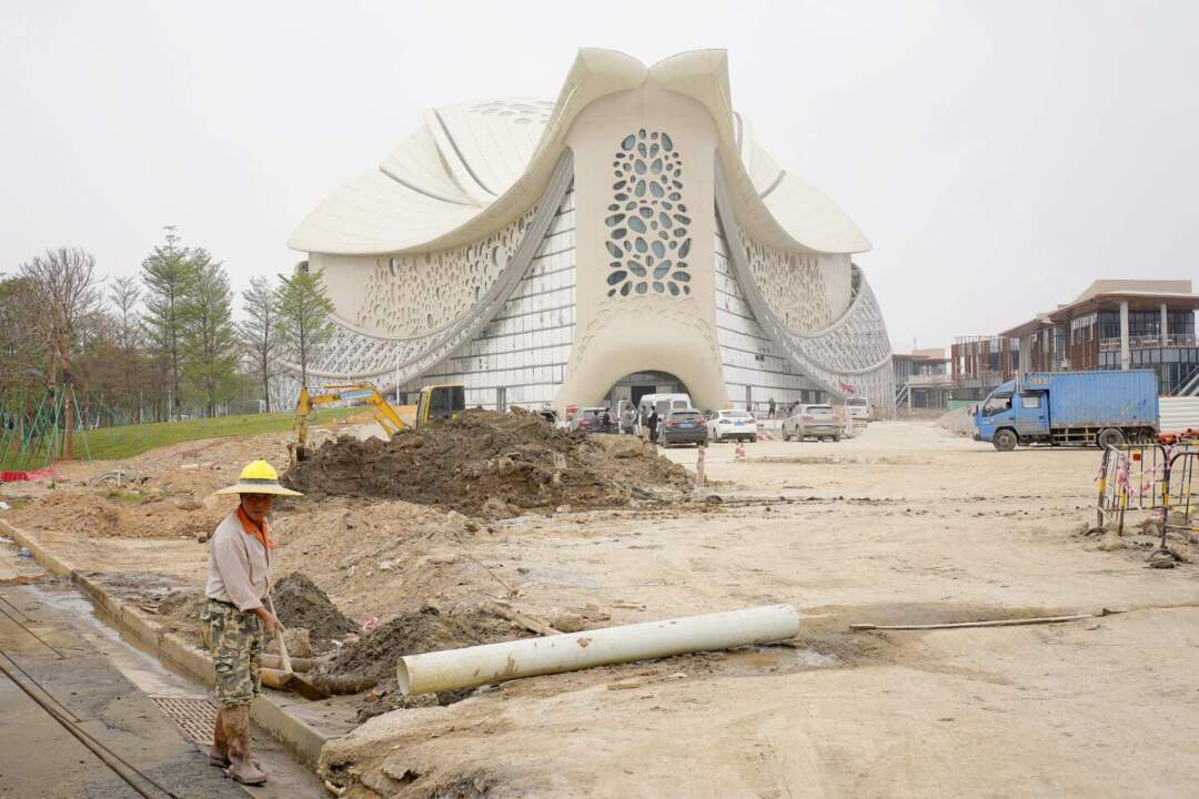 一名頭戴草帽的工人於中醫藥科技創意博物館外用鐵鏟工作。
